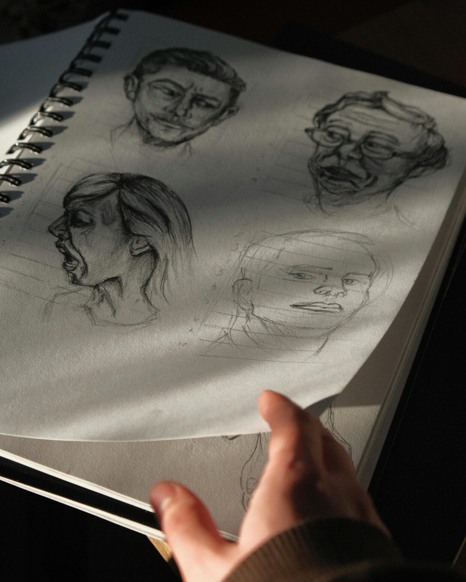 A notebook page with artistic pencil sketches captured in dramatic shadow and light.